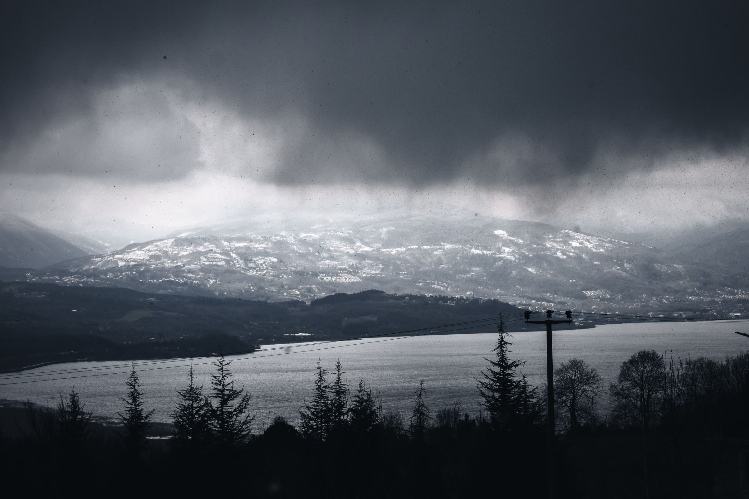Dark cloud over a lake and snow-covered mountains