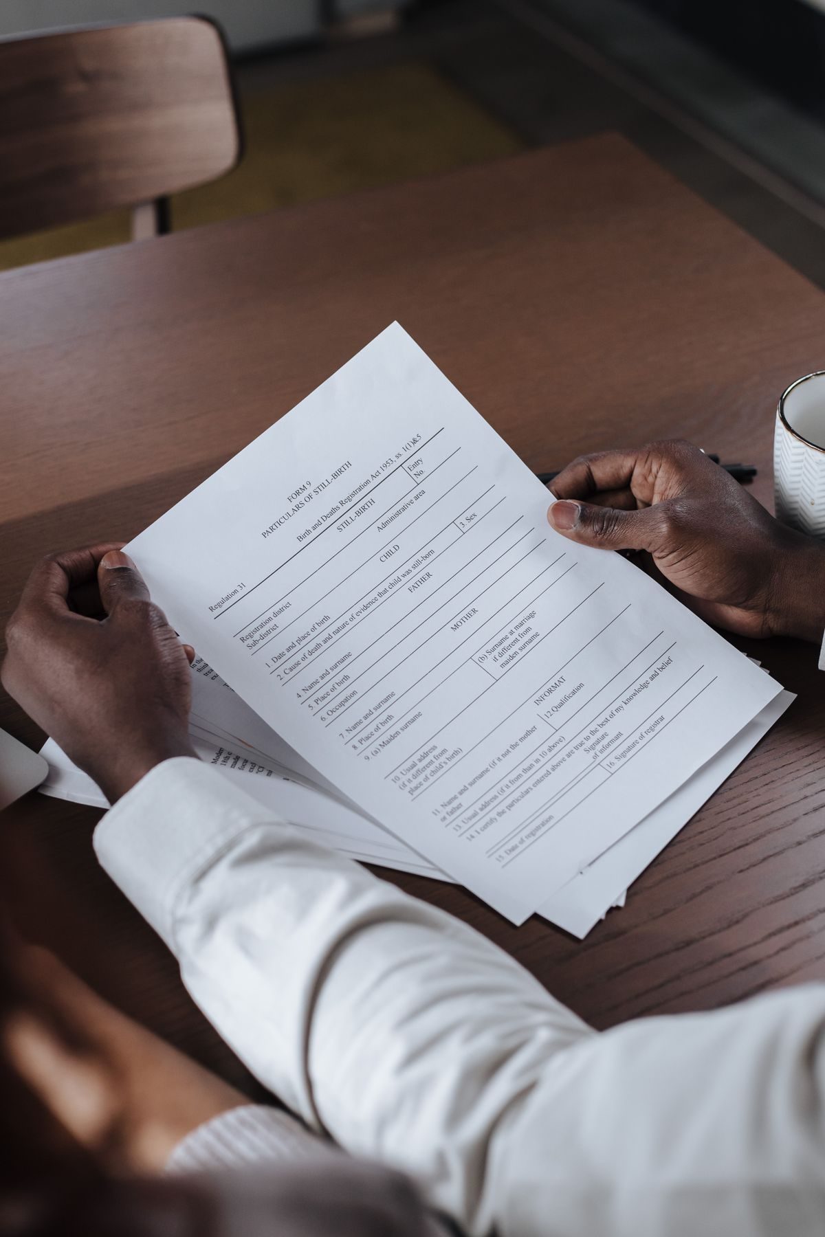 Someone reading through documents at a wooden table