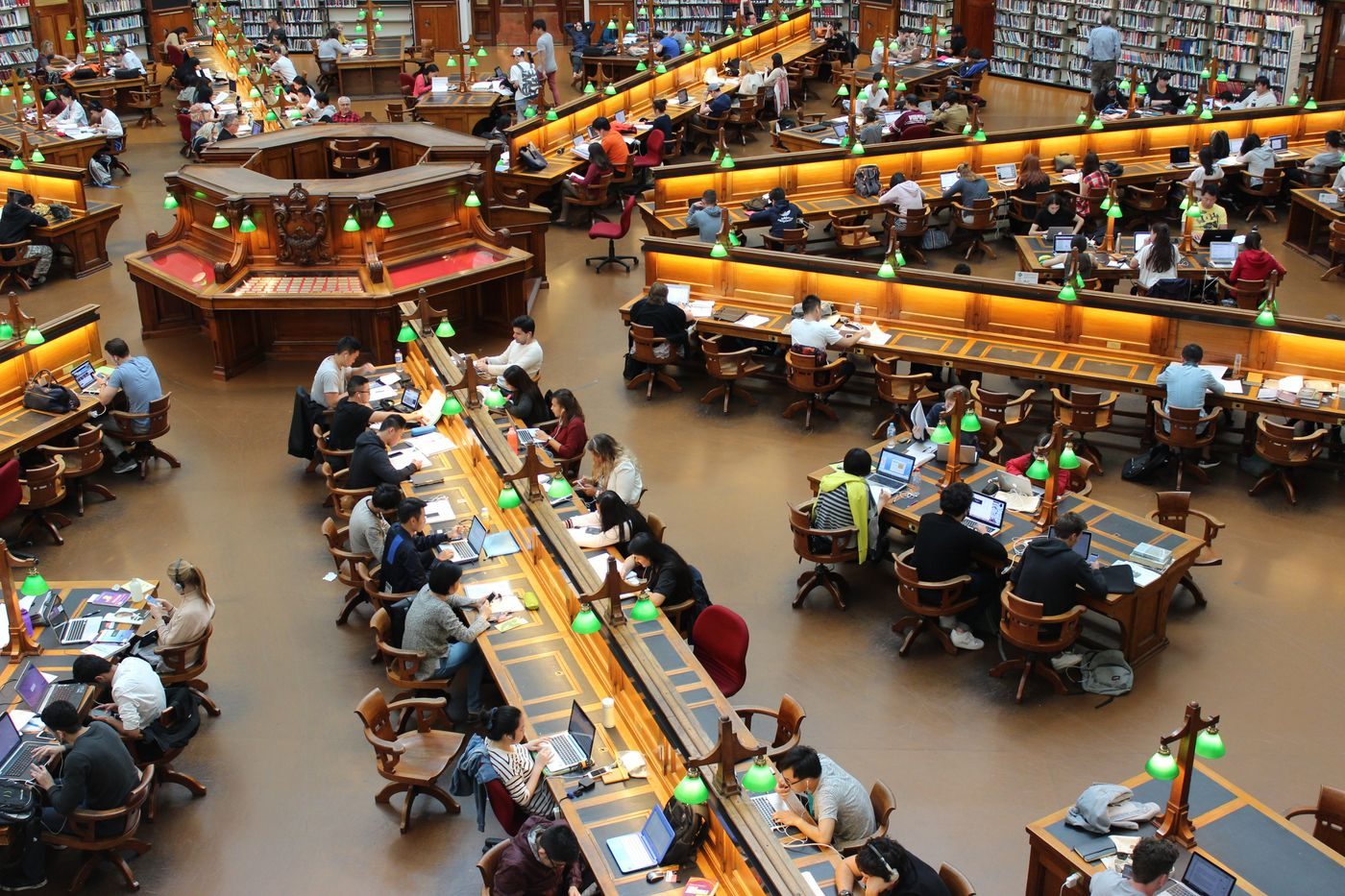 Students working at long desks in a library reading room
